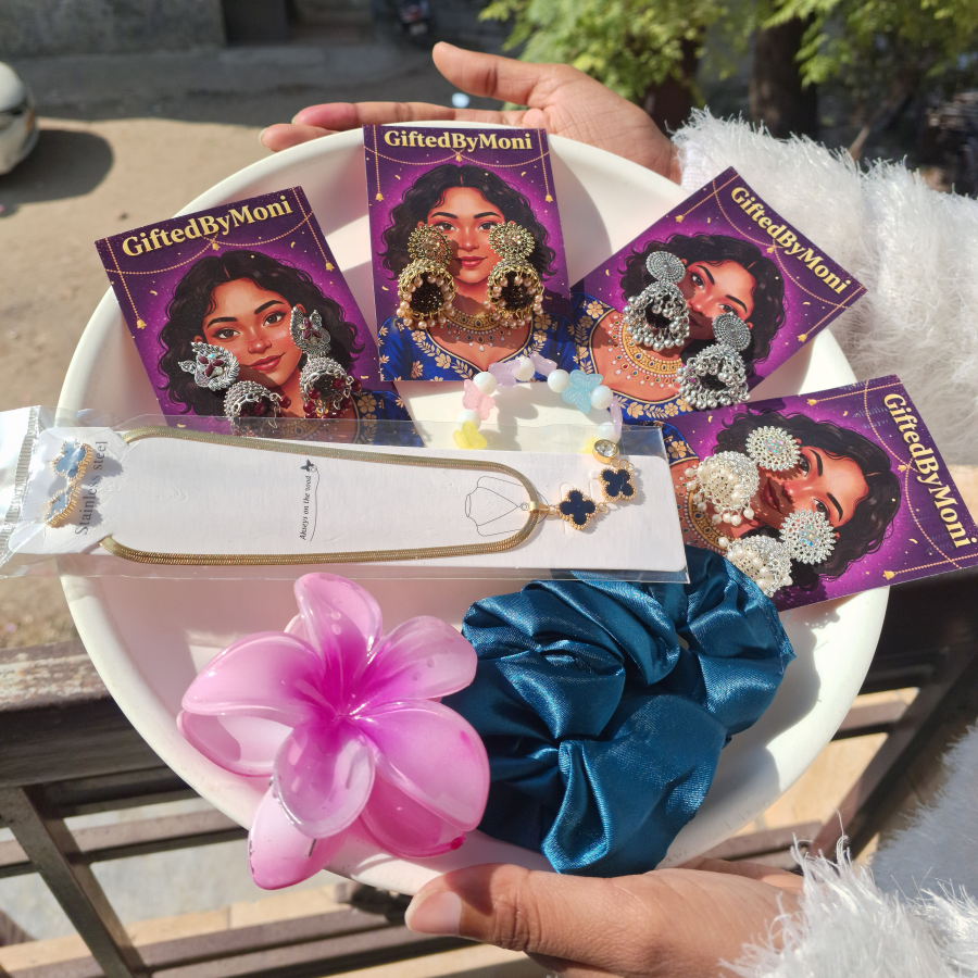 Hand holding 'Gifted by Mom' products with decorative items on a table outdoors.